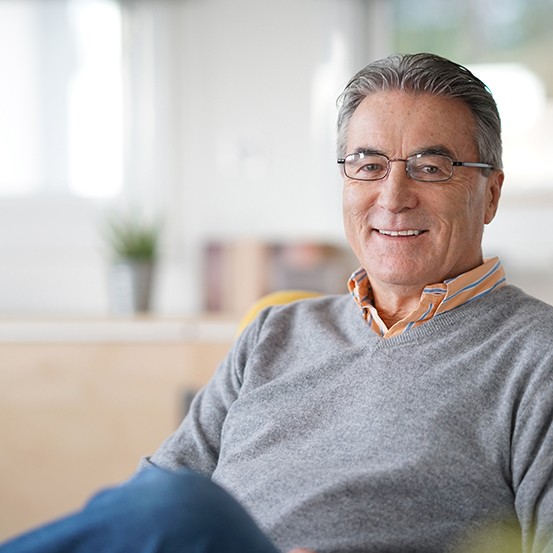 Senior man sitting on couch smiling